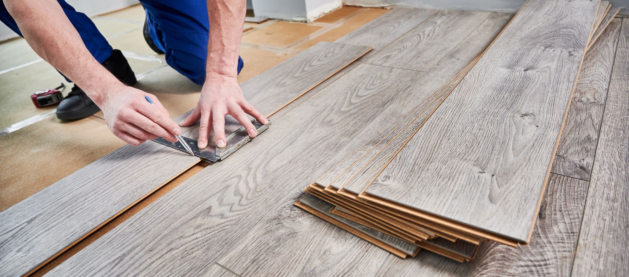 Flooring being installed with hands shown measuring the installation