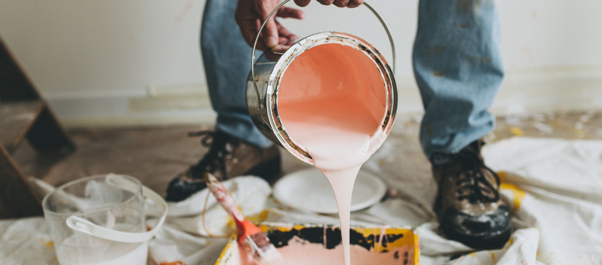 Pink paint being poured our of a paint can.